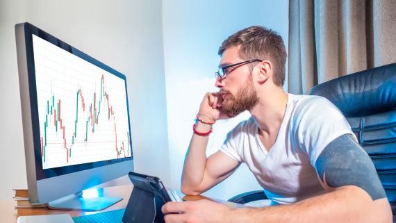 Un jeune homme analyse des graphiques de résultats financiers sur son ordinateur.