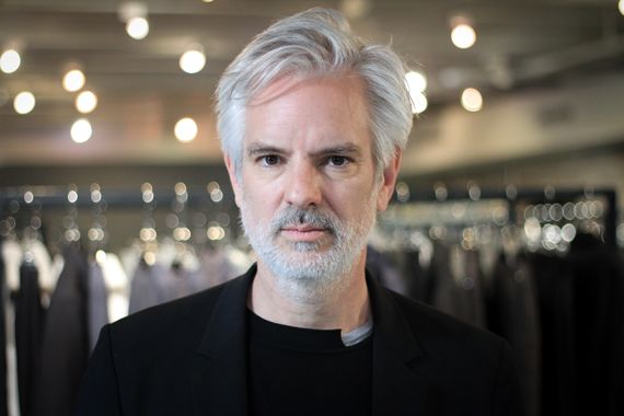 Le créateur Philippe Dubuc devant des supports de vêtements.