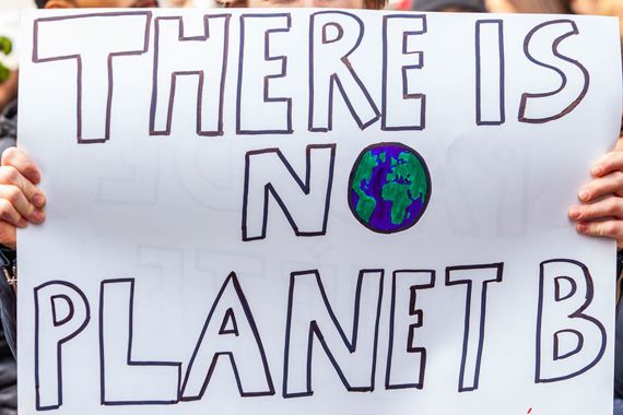Une personne tenant une pancarte où il est inscrit There is no Planet B.