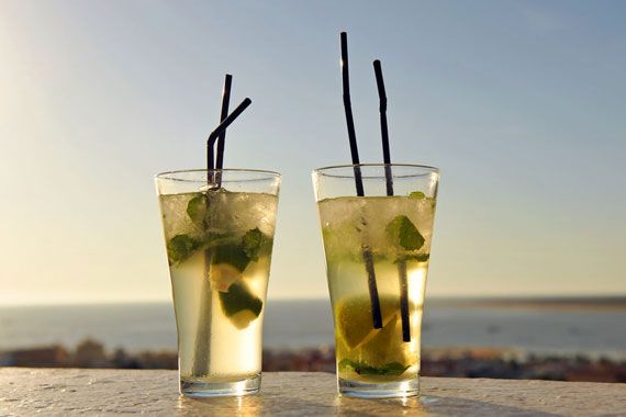 Deux verres de mojitos sur le bord d'une plage par un coucher de Soleil.