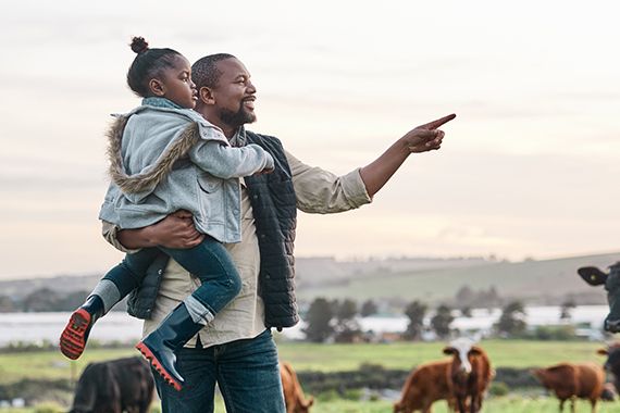 Un père montre à sa fille un champ de vache