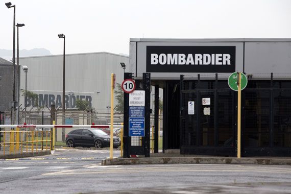 Une barrière barre le chemin devant un bâtiment sur lequel est marqué Bombardier