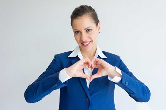 Une femme d'affaires qui fait un signe de coeur avec ses mains.