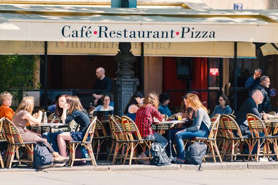 Des touristes sont assis sur une terrasse d'un café à Paris