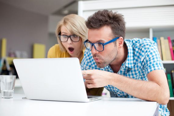 Un homme et une femme surpris devant un écran d'ordinateur.