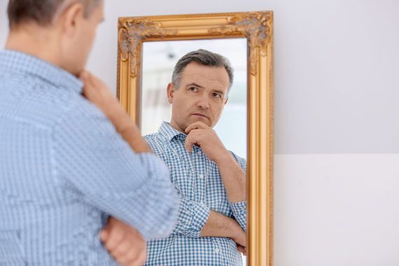Un homme se regarde dans un miroir